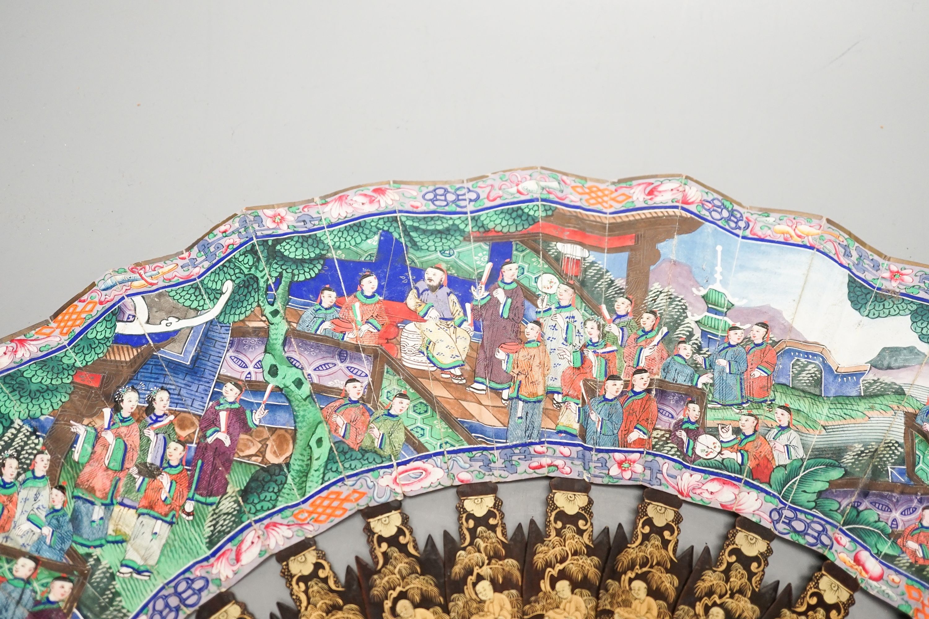 A Chinese export gilt decorated lacquer fan and box, mid 19th century, the appliqué work paper fan leaf decorated with figures amid pavilions and trees, box 32cm